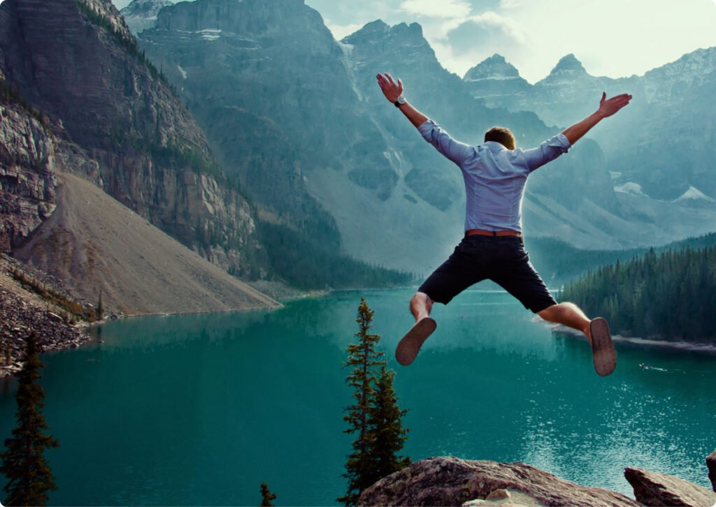 Man jumping with arms outstretched at Moraine Lake, Banff National Park.
