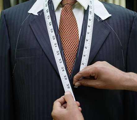 Tailor measuring a suit with measuring tape. Custom menswear.